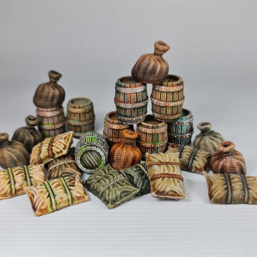 A hand-painted 3D printed miniature of a wooden barrel, held between fingers. The barrel has green staves, silver-painted bands with rivets, and a weathered top.