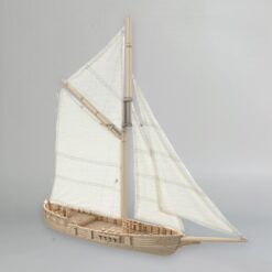 3D printed model of a historical single-mast trading sloop. The ship has a detailed wooden hull, a tall mast with a gaff rig, and sails made of white fabric. The deck shows planking details and railings.
